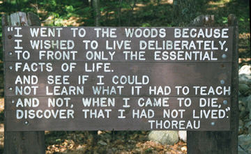 A sign greeting visitors at Walden Pond which explains Thoreau's reasoning for living in the woods.